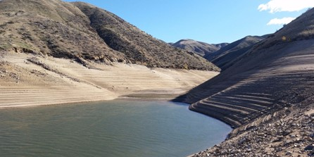 low water level in reservoir surrounded by dry brown landscape