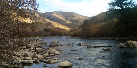 rocky stream with dry brown hills in the distance